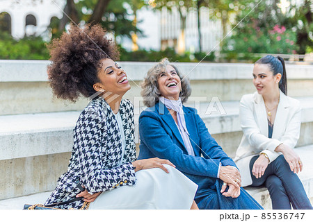 women seated with their legs crossed and dressed in suits 85536747