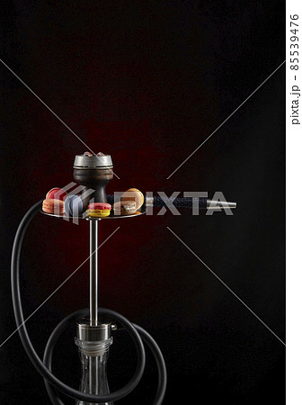 Modern hookah decorated with macaroon of various colors on a dark background. Vertical inage. The culture of serving shisha. Modern hookah decorated with macaroon of various colors on a dark background. Vertical inage. The culture of serving shisha. 85539476