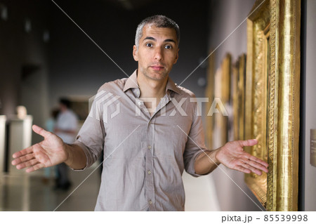 Adult man is visiting museum and looking at the pictures Adult man is visiting museum and looking at the pictures 85539998