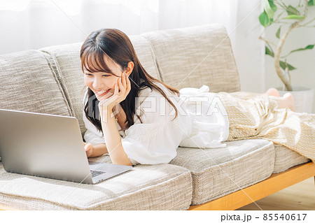 ソファで寝転がりながらパソコンを使う女性 85540617