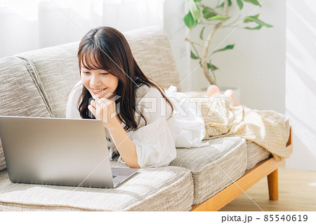 ソファで寝転がりながらパソコンを使う女性 85540619