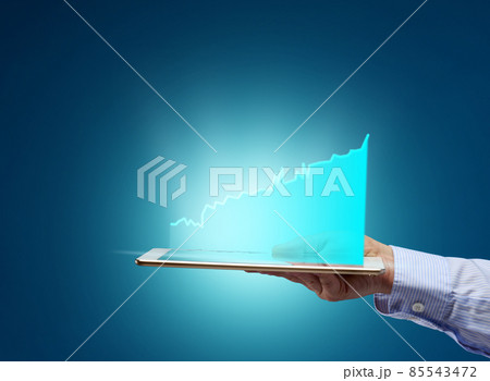 female hand holding electronic tablet with holographic graphic on blue background female hand holding electronic tablet with holographic graphic on blue background 85543472