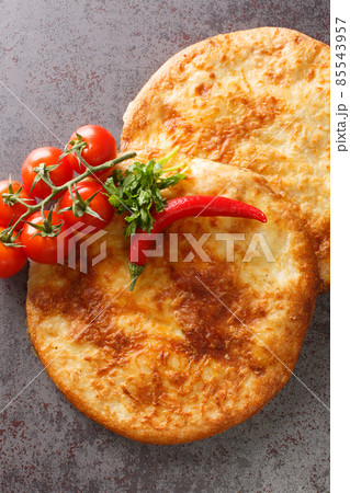 Georgian flat bread khachapuri with cheese close-up on the table. Vertical top view Georgian flat bread khachapuri with cheese close-up on the table. Vertical top view 85543957