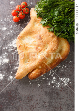 Shotis puri or shoti is a Georgian bread made with whole wheat flour, salt, water, and yeast close up. Vertical top view Shotis puri or shoti is a Georgian bread made with whole wheat flour, salt, water, and yeast close up. Vertical top view 85544017