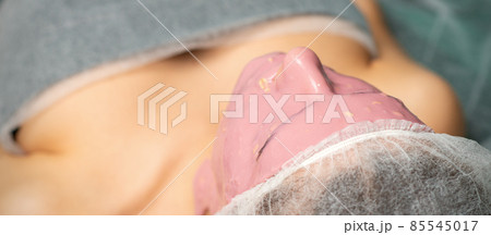 Women skin beauty treatment care. Young woman with alginate cosmetic pink mask on facial skin in beauty spa salon. Women skin beauty treatment care. Young woman with alginate cosmetic pink mask on facial skin in beauty spa salon. 85545017