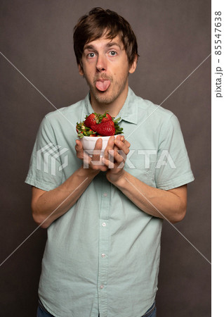 Young man with strawberries on grey 85547638