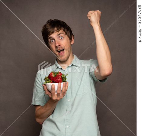 Young man with strawberries on grey 85547639