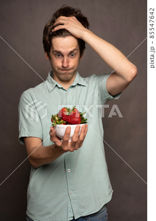 Young man with strawberries on grey 85547642