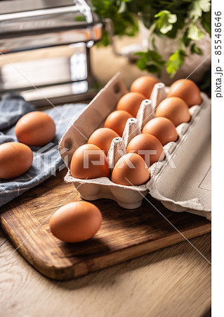 Eggs in a cardboard box on a wooden board in the kitchen. 85548646