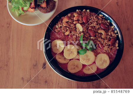 Top view of a healthy vegan smoothie bowl made of red dragon fruit, bananas with oats cashew nuts and almonds 85548769