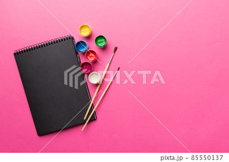 Album pages and paints, pencils, brush on a colored background. Top view with empty space. workplace for creativity. home teaching concept drawing Album pages and paints, pencils, brush on a colored background. Top view with empty space. workplace for creativity. home teaching concept drawing 85550137