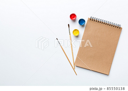 Album pages and paints, pencils, brush on a colored background. Top view with empty space. workplace for creativity. home teaching concept drawing Album pages and paints, pencils, brush on a colored background. Top view with empty space. workplace for creativity. home teaching concept drawing 85550138