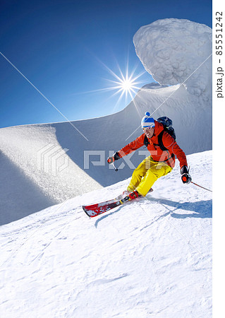 Skier skiing downhill in high mountains against blue sky Skier skiing downhill in high mountains against blue sky 85551242