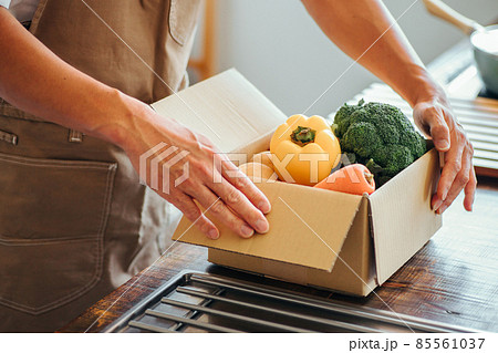 キッチンでダンボールに入った野菜を持つ男性 85561037