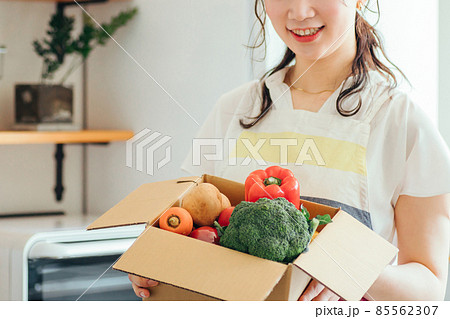 キッチンでダンボールに入った野菜を持つ女性（顔なし） 85562307