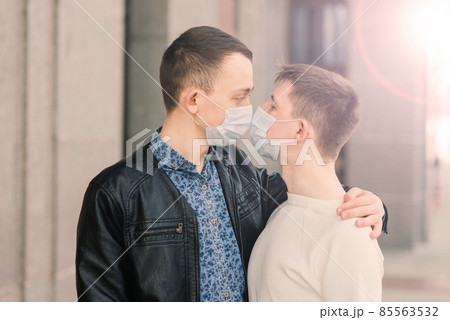 Young gay couple wearing medical mask hugging at city. Young gay couple wearing medical mask hugging at city. 85563532