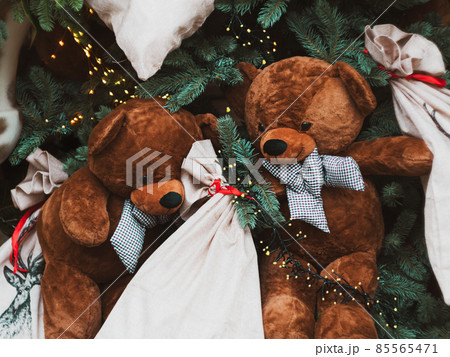 Soft brown bear toys on shop window Christmas fair store decorated with gifts garland lights illuminated New year retail 85565471