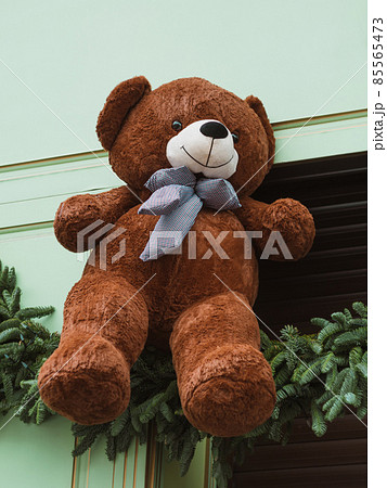 Soft brown bear toys on shop window Christmas fair store decorated with gifts garland lights illuminated New year retail 85565473