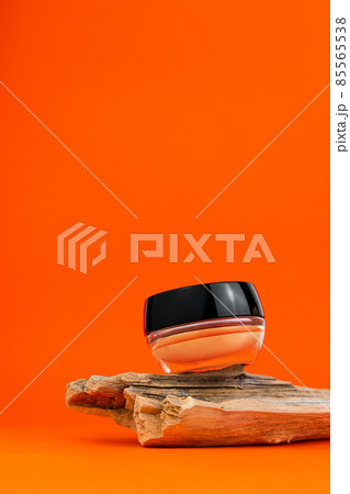 Cosmetic face BB cream tonal foundation glass jar mockup natural wood podium orange background. Balancing makeup product Cosmetic face BB cream tonal foundation glass jar mockup natural wood podium orange background. Balancing makeup product 85565538