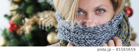 Portrait of young woman wrapped in scarf on background of Christmas tree 85565659