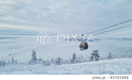 Empty white red closed ski lift cabin no people and white dramatic snowy mountains background. End of season concept. Ski resorts closure Empty white red closed ski lift cabin no people and white dramatic snowy mountains background. End of season concept. Ski resorts closure 85565866