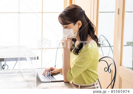コロナ飛沫感染対策をしてパソコンで仕事する若い女性（ビジネス） 85565974
