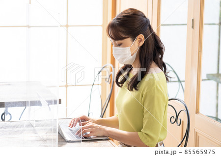 コロナ飛沫感染対策をしてパソコンで仕事する若い女性（ビジネス） 85565975