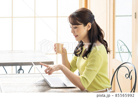 カフェでパソコンを使って仕事をする若い女性（ビジネス） 85565992