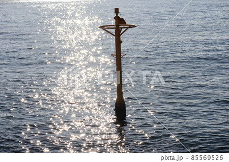 太陽の光でキラキラ光る道の海面の海と小さな灯台のような鉄塔のある