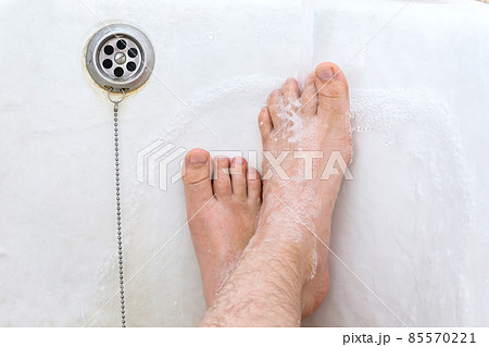 Man washes his dirty feet under water 85570221