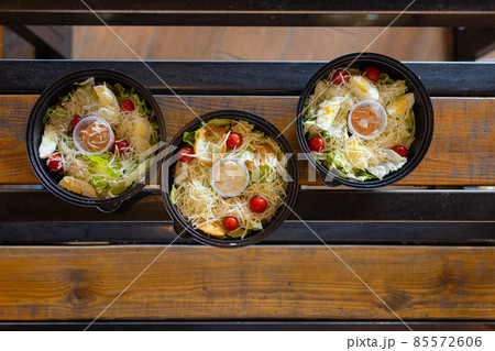 Variety of clean dieting salads in plastic package and green measuring tape on rustic background, top view. Healthy clean food concept. Variety of clean dieting salads in plastic package and green measuring tape on rustic background, top view. Healthy clean food concept. 85572606