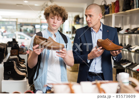 Man and teenage boy choosing dress shoes in shoe boutique 85573609