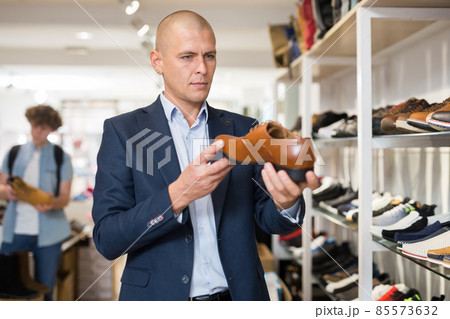 Handsome man chooses classic brown shoes in shoe store 85573632