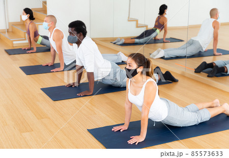 People in protective masks practice yoga in gym 85573633