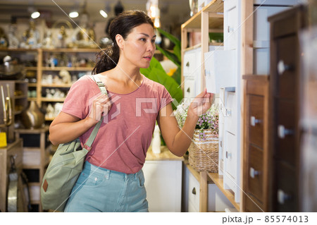 Asian female choosing wooden commode in store 85574013