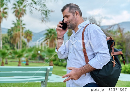 Mature man talking on the phone outdoors. 85574367