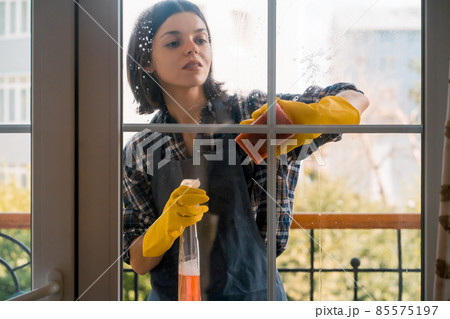 Woman washes the windows with a detergent. Woman washes the windows with a detergent. 85575197