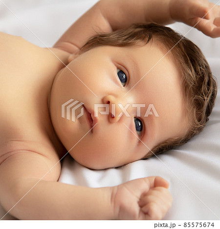 Newborn baby in a wrap on white blanket. Beautiful 85575674