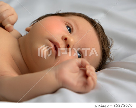 Newborn baby in a wrap on white blanket. Beautiful 85575676