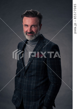 Portrait of a stylish elegant senior businessman with a beard and casual business clothes in photo studio isolated on dark background gesturing with hands Portrait of a stylish elegant senior businessman with a beard and casual business clothes in photo studio isolated on dark background gesturing with hands 85577085