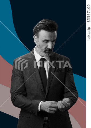 Black and white portrait of a stylish elegant senior businessman with a beard and casual business clothes against retro colorful pattern design background gesturing with hands 85577100