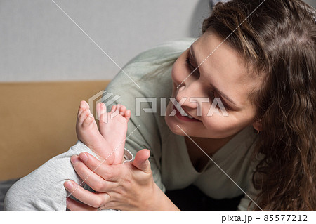 Mom's love for the baby. Brunette woman holding legs of baby Mom's love for the baby. Brunette woman holding legs of baby 85577212