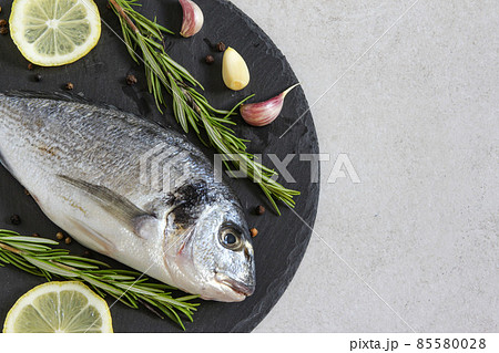 One fresh raw sea organic dorado or sea bream with spices and lemon 85580028
