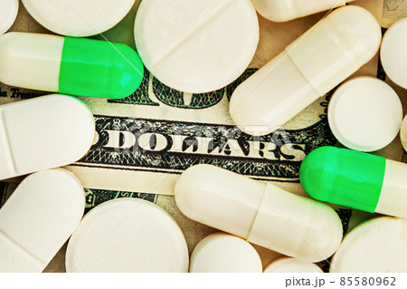 Covid-19 coronavirus pills Medicines costs dollars are scattered across the hundred dollar bills. A 85580962