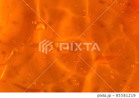 Texture of transparent yellow gel with air bubbles and waves on orange background. Concept of skin moisturizing, body care and prevention of covid19. Liquid beauty product closeup. Backdrop, flat lay Texture of transparent yellow gel with air bubbles and waves on orange background. Concept of skin moisturizing, body care and prevention of covid19. Liquid beauty product closeup. Backdrop, flat lay 85581219