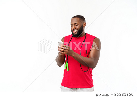 Mature fit African American man texting on mobile and holding elastic rope. 85581350
