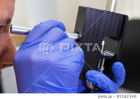 Scientist checking the condition of nebulizer needle from LC MS qTOF system using adjustment fixture and magnifier. Scientist checking the condition of nebulizer needle from LC MS qTOF system using adjustment fixture and magnifier. 85582340