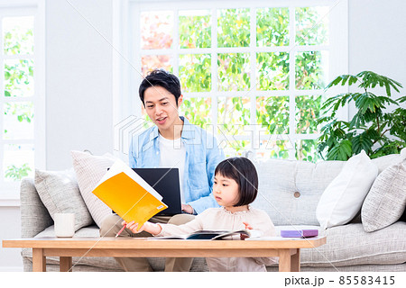 ソファに座ってノートパソコンで仕事をするパパと学校の話をする子供 ソファに座ってノートパソコンで仕事をするパパと学校の話をする子供 85583415