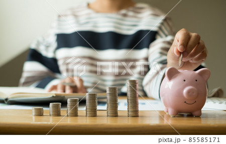 Woman's hand. putting coins in the piggy bank with coins, saving money with coins, stepping into a successful growing business, and saving for thought in retirement. Retirement savings concept 85585171