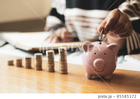 Woman's hand. putting coins in the piggy bank with coins, saving money with coins, stepping into a successful growing business, and saving for thought in retirement. Retirement savings concept 85585172